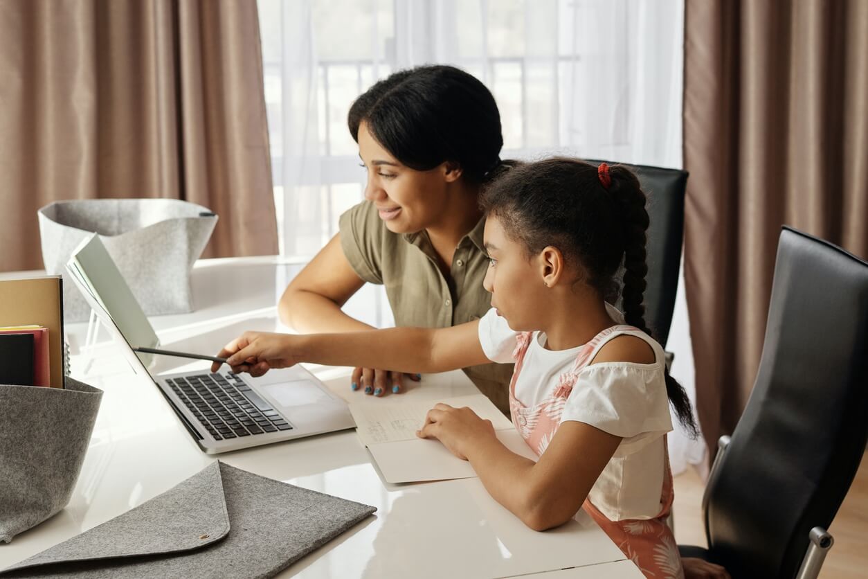 Tutor teaching a child with reading software on a computer